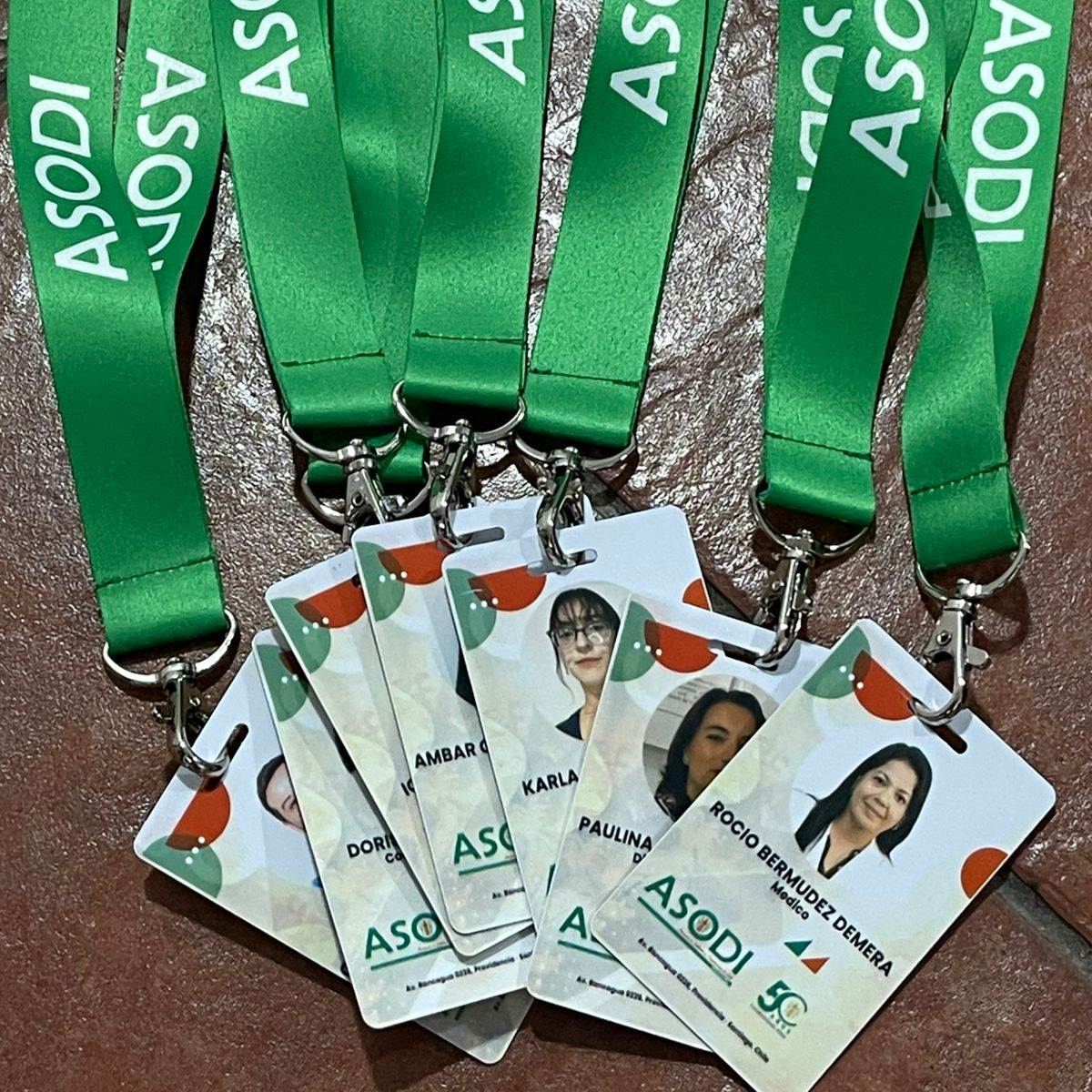 Credenciales PVC de identificación con cintas verdes y logo de ASODI, mostrando nombres y fotos de varios miembros.