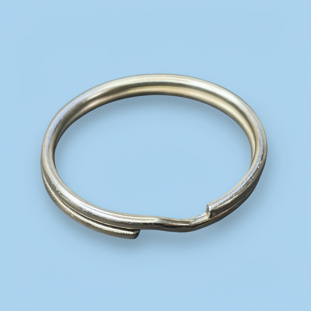 Anillo metálico plateado con abertura, sobre fondo azul claro.