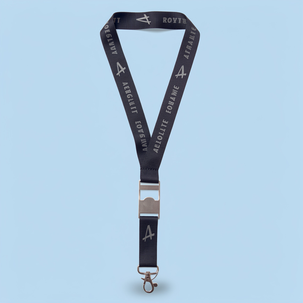 Lanyard de color negro con letras estampadas grises, con destapador metálico y mosquetón, sobre fondo celeste